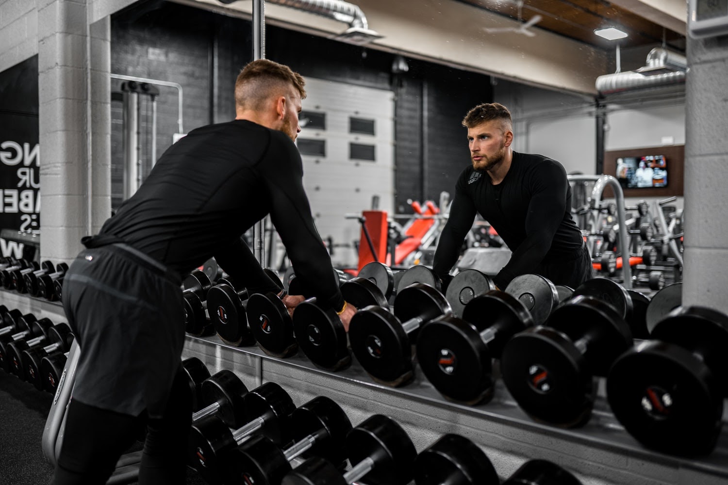 man looking in mirror at gym